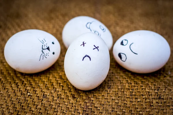 Close up view of eggs with funny faces drawn on them.