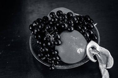 taze üzüm ve ahşap yüzeyde bir cam kabın içinde portakal.