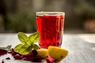 Ahşap yüzeyde popüler Hint içki dilimlenmiş limon, gül yaprakları ve nane yaprakları.