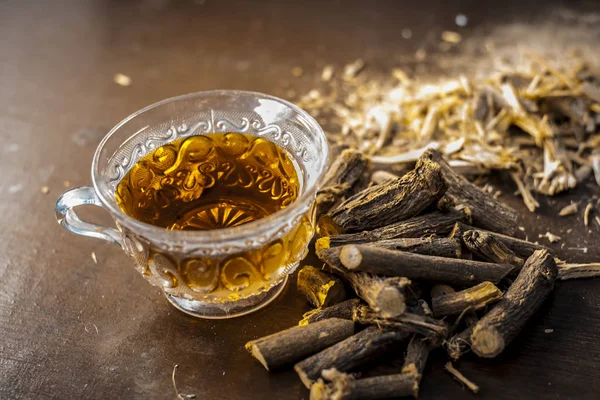Meyan kökü kökleri üzerinde ahşap arka plan ile çay kapatır