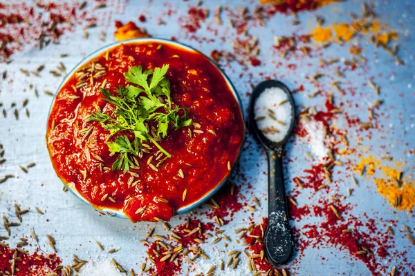 Top view of Indian tomato chutney with spices on silver table