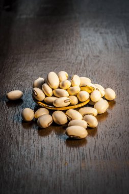 Ayurveda ot kuanch, cowhage, Mucuna pruriens karanlık Gotik renkler kahverengi ahşap yüzey üzerinde tozu ile yakın çekim.