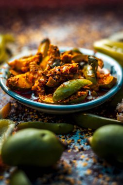 Close up of traditional raw mango pickle with ingredients on table clipart