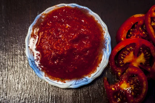 Close up of sliced tomato with puree on wooden surface