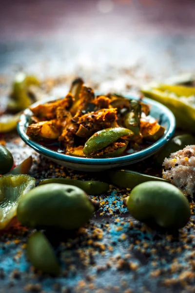 Close up of traditional raw mango pickle with ingredients on table