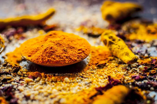 Close up of FACE PACK OF BANANA with all its other ingredients i.e. Turmeric powder, rose petals, and raw turmeric on a wooden surface for good and brighter skin.