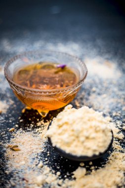 Yulaf yüz paketi Yani gül suyu, yulaf, gram un ve bal kaplıcada temiz ve pürüzsüz cilt için kullanılan ahşap yüzeye yakın çekim.