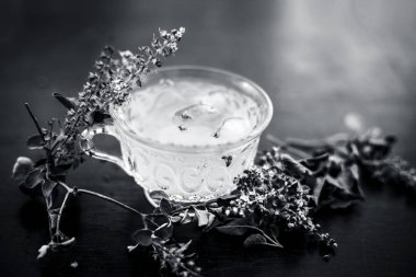 Şeffaf bardakta beyaz renkli buzlu çay. İçinde buz küpleri ve taze taze fesleğen yaprakları var..