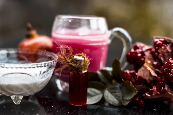 Close up of pomegranate juice and essence with milk on wooden surface