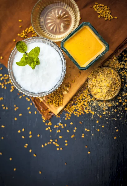 Herbal and organic home remedy for hair fall i.e. Egg white mixed with curd and fenugreek seeeds in a bowl,On wooden surface with raw fenugreek or methi seeds and curd with egg shells,Close up view.