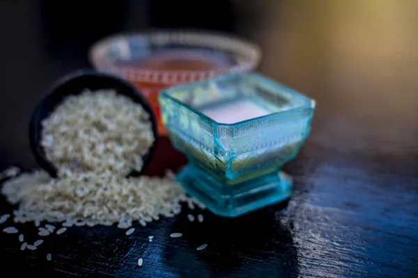 Close up of herbal face pack of rice flour with castor oil and rose water used to reduce or cleaning acne and pimples in a glass bowl with raw rice flour and rice.