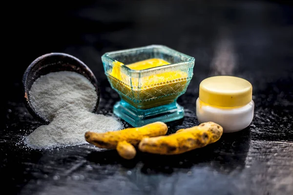 Close up of face pack of rice flour with fresh face cream and turmeric powder on wooden surface in a glass bowl with some raw turmeric roots.Used to supple and to soft the skin.