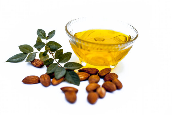 Close up of raw almond with its extracted organic oil in a transparent glass bowl isolated on white.