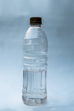 Plastik su şişesi içine biraz su sahip beyaz ya da mavi arka plan üzerinde izole. Görünümü kapatın.