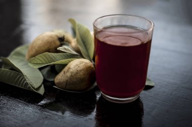 Kırmızı guava ya da amarood ya da jamrukh ile ham guava saydam bir cam ve ahşap yüzeyde yaprakları organik meyve suyu kapat.