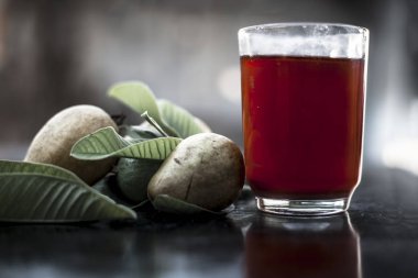 Kırmızı guava ya da amarood ya da jamrukh ile ham guava saydam bir cam ve ahşap yüzeyde yaprakları organik meyve suyu kapat.