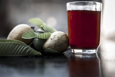 Kırmızı guava ya da amarood ya da jamrukh ile ham guava saydam bir cam ve ahşap yüzeyde yaprakları organik meyve suyu kapat.