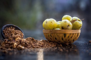 Ham amla veya Phyllanthus emblica veya onun yüz paketi, içecekler ve ahşap yüzeyde doğal ilaçlar kullanılan bir kil kase kuru tohum tozu ile meyve sepeti Hint bektaşi üzümü yakın çekim.