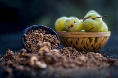 Ham amla veya Phyllanthus emblica veya onun yüz paketi, içecekler ve ahşap yüzeyde doğal ilaçlar kullanılan bir kil kase kuru tohum tozu ile meyve sepeti Hint bektaşi üzümü yakın çekim.