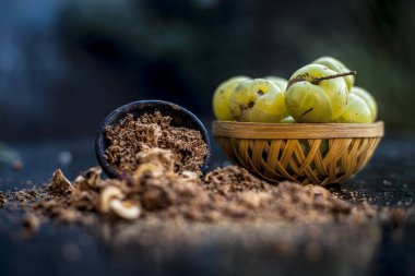 Ham amla veya Phyllanthus emblica veya onun yüz paketi, içecekler ve ahşap yüzeyde doğal ilaçlar kullanılan bir kil kase kuru tohum tozu ile meyve sepeti Hint bektaşi üzümü yakın çekim.