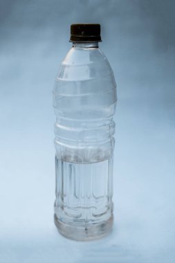 Plastik su şişesi içine biraz su sahip beyaz ya da mavi arka plan üzerinde izole. Görünümü kapatın.