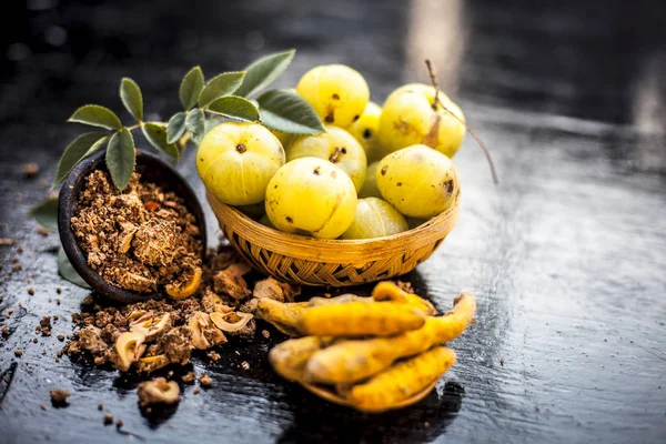 Close up of Indian gooseberry or amla with turmeric and lemon juice on wooden surface in a glass bowl to get rid of Blemishes,acne and pimples.