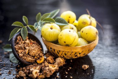 Ham amla veya Phyllanthus emblica veya onun yüz paketi, içecekler ve ahşap yüzeyde doğal ilaçlar kullanılan bir kil kase kuru tohum tozu ile meyve sepeti Hint bektaşi üzümü yakın çekim.