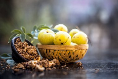 Ham amla veya Phyllanthus emblica veya onun yüz paketi, içecekler ve ahşap yüzeyde doğal ilaçlar kullanılan bir kil kase kuru tohum tozu ile meyve sepeti Hint bektaşi üzümü yakın çekim.