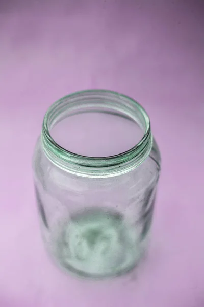 Close up of empty glass jar or storage jar or glass container isolated on pink surface.