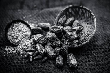 Kahverengi yüzeyde bir meyve sepetinde kharek veya Phoenix dactylifera kuru tarihler yakın. Siyah beyaz