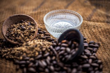 Ev çare ham muhallebi elma tohumları ile bir cam kase su ve organik ham Hindistan cevizi yağı ile karışık kurutulmuş ve toz iyi kahverengi renkli yüzey Yani muhallebi elma tohumları üzerinde bit veya Joon tedavi etmek.