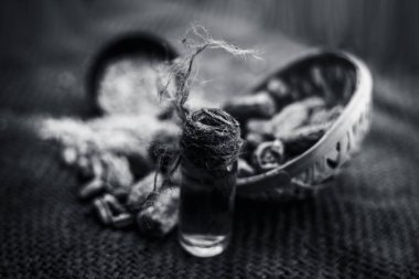 Kurutulmuş hurma veya sukhi khajoor veya Phoenix dactylifera ham kurutulmuş tarihleri ve toz ile kahverengi yüzeyüzerinde şeffaf bir cam şişe içinde kharek Uçucu yağ. Siyah beyaz