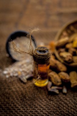 Kurutulmuş hurma veya sukhi khajoor veya Phoenix dactylifera ham kurutulmuş tarihleri ve tozu ile kahverengi yüzeyüzerinde şeffaf bir cam şişe içinde kharek Uçucu yağ.