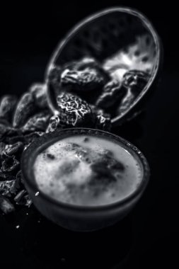 Ahşap yüzey üzerinde popüler Hint ve Asya Kış içecek yakın yani Kharek ka dudh veya kurutulmuş hurma süt süt, kurutulmuş hurma, kaju fıstığı, badem kuru meyve ve şeker oluşan. siyah beyaz