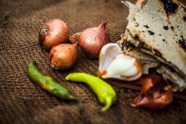 İnci darı roti veya chapati veya bajra veya bajri ki roti ile bazı soğan ve biber oluşan gunny çanta arka plan üzerinde yemek veya köylü öğle yemeği ya da tipik bir çiftçi yakın.