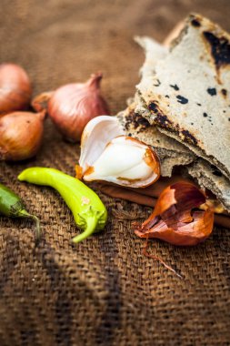 İnci darı roti veya chapati veya bajra veya bajri ki roti ile bazı soğan ve biber oluşan gunny çanta arka plan üzerinde yemek veya köylü öğle yemeği ya da tipik bir çiftçi yakın.