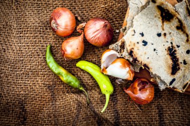 İnci darı roti veya chapati veya bajra veya bajri ki roti ile bazı soğan ve biber oluşan gunny çanta arka plan üzerinde yemek veya köylü öğle yemeği ya da tipik bir çiftçi yakın.