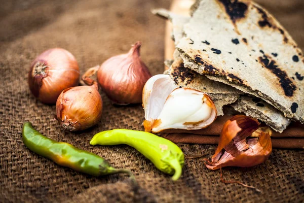 İnci darı roti veya chapati veya bajra veya bajri ki roti ile bazı soğan ve biber oluşan gunny çanta arka plan üzerinde yemek veya köylü öğle yemeği ya da tipik bir çiftçi yakın.