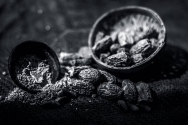 Siyah renkli kil kase içinde toz ile ham kurutulmuş organik kharek veya kurutulmuş hurma veya Phoenix dactylifera kapatın. siyah beyaz