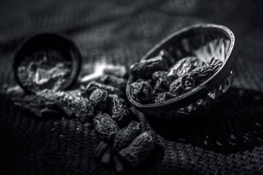 Siyah renkli kil kase içinde toz ile ham kurutulmuş organik kharek veya kurutulmuş hurma veya Phoenix dactylifera kapatın. siyah beyaz