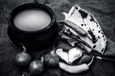 Bazı soğan ve biber, ayran ile inci darı roti veya chapati veya bajra veya bajri ki roti oluşan gunny çanta arka plan üzerinde yemek veya köylü öğle yemeği ya da tipik bir çiftçi kapatın. siyah beyaz