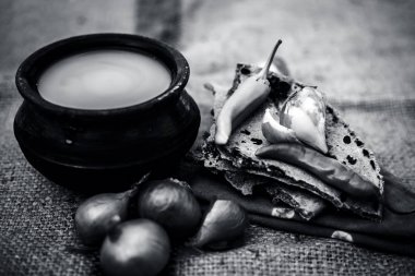 Bazı soğan ve biber, ayran ile inci darı roti veya chapati veya bajra veya bajri ki roti oluşan gunny çanta arka plan üzerinde yemek veya köylü öğle yemeği ya da tipik bir çiftçi kapatın. siyah beyaz