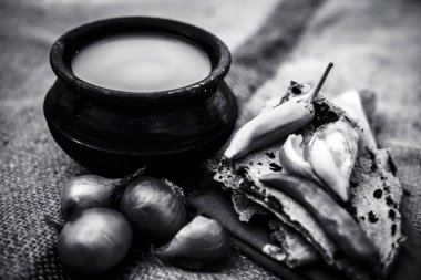 Bazı soğan ve biber, ayran ile inci darı roti veya chapati veya bajra veya bajri ki roti oluşan gunny çanta arka plan üzerinde yemek veya köylü öğle yemeği ya da tipik bir çiftçi kapatın. siyah beyaz