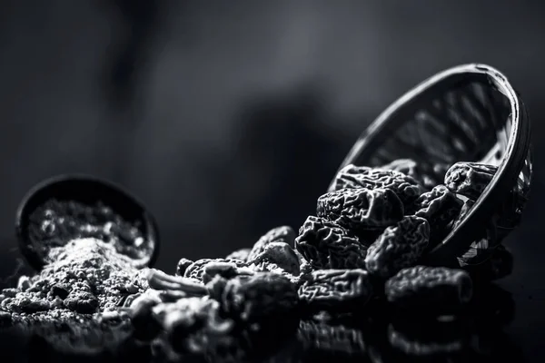 Close up of Dried dates or kharek or sukhi khajoor in a hamper with its powder on wooden surface. black and white