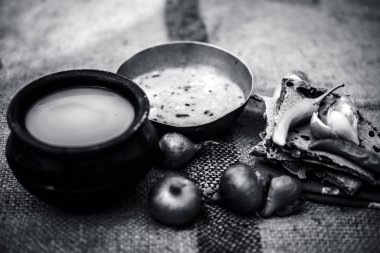 Beyaz mercimek, inci darı roti veya chapati ve ayran veya yeşil biber ve bazı soğan ile şabaile gunny çanta arka plan üzerinde yoksul adamın tam süt kapatın. siyah beyaz