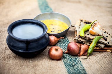 Beyaz mercimek, inci darı roti veya chapati ve ayran veya yeşil biber ve bazı soğan ile şabaile gunny çanta arka plan üzerinde yoksul adamın tam süt kapatın.