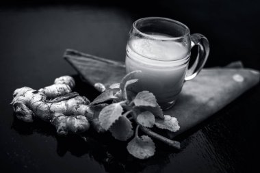 Bazı çiğ zencefil ve ajwain yaprakları ile ahşap yüzeyüzerinde şeffaf bir cam zencefil organik suyu kapatın. siyah beyaz