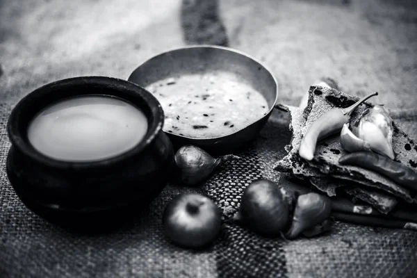 Beyaz mercimek, inci darı roti veya chapati ve ayran veya yeşil biber ve bazı soğan ile şabaile gunny çanta arka plan üzerinde yoksul adamın tam süt kapatın. siyah beyaz