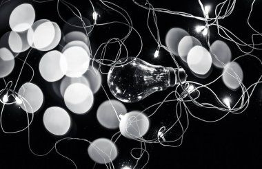 Renkli bulanık arka plan veya onunla Noel ışıkları bokeh ile ahşap yüzeyüzerinde bir ampul yakın.