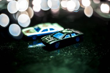 Siyah ve beyaz renkli iki minyatür araba veya bulanık arka plan veya bokeh veya Noel renkli ışıklar ile ahşap yüzey üzerinde oyuncak araba yakın.